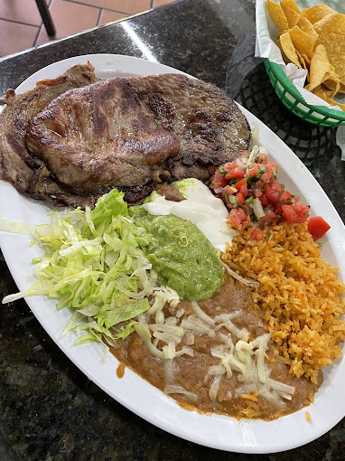 A plate of steak with salsa, guacamole and sour cream, and beans and rice.