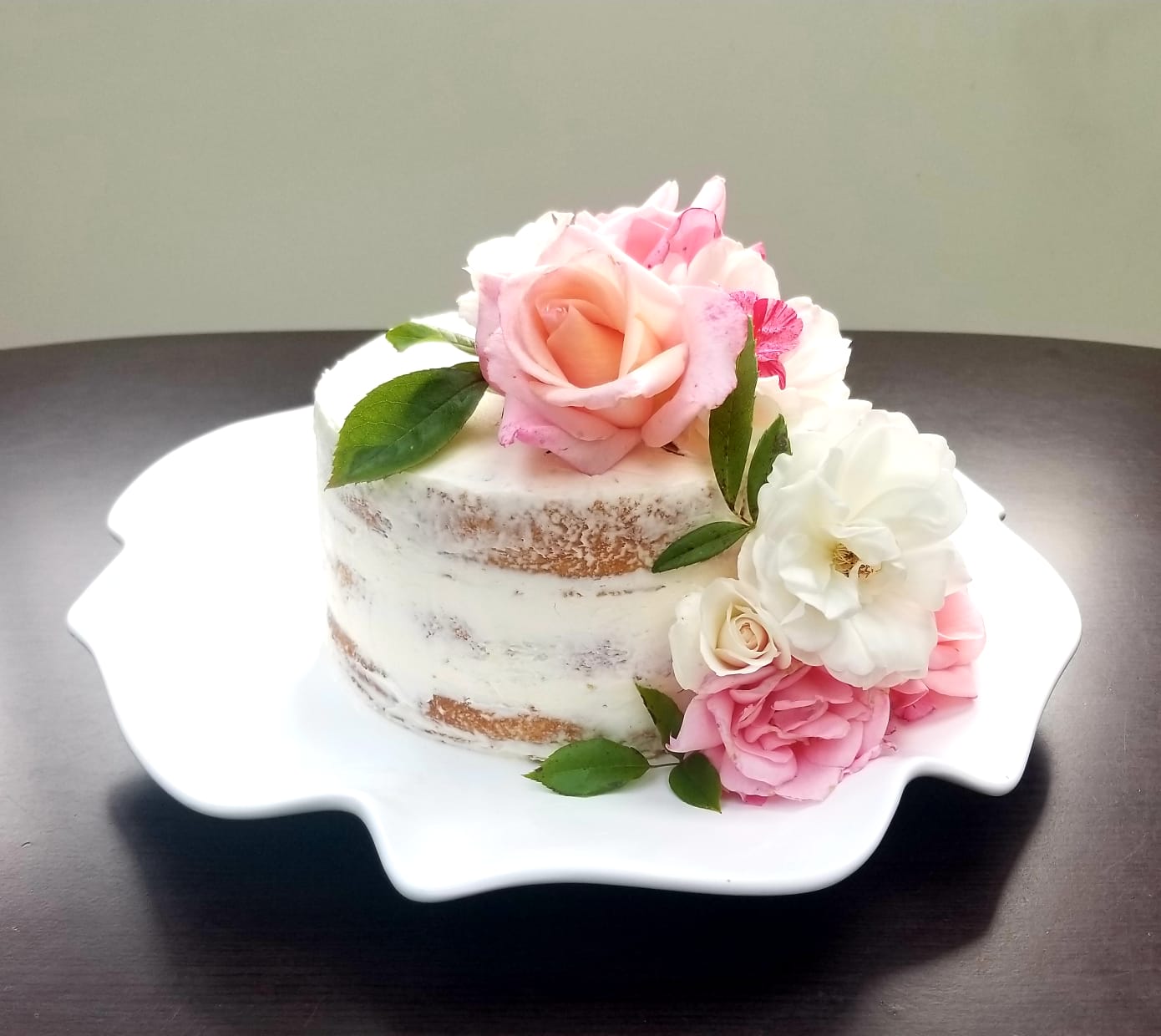 A small cake covered in powdered sugar and roses.