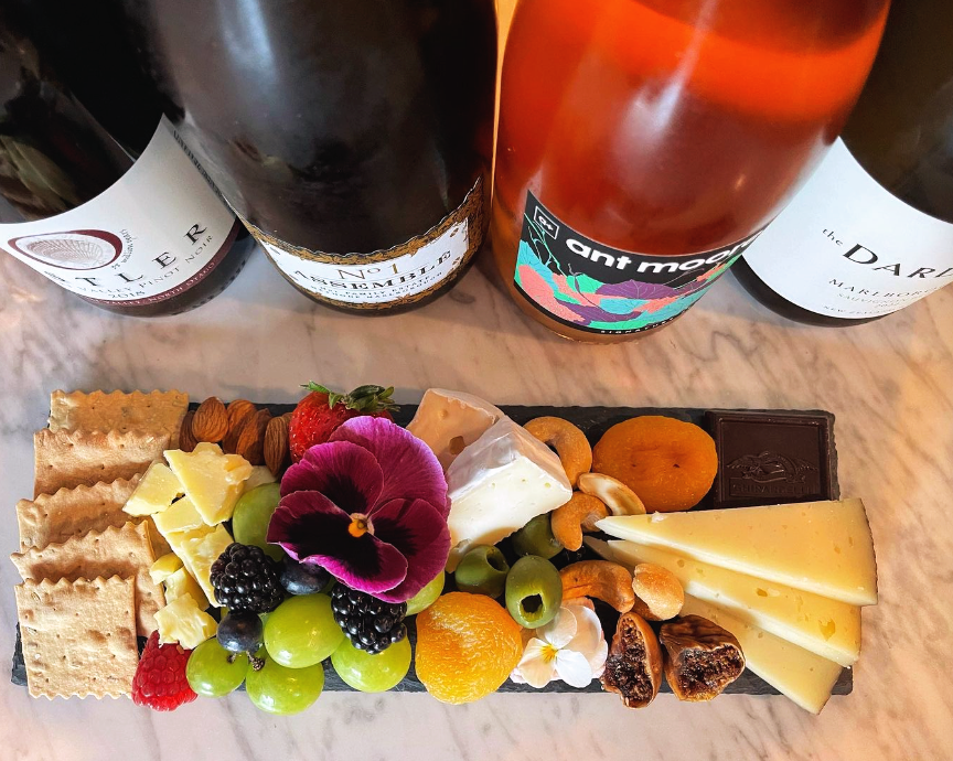 A small charcuterie board next to bottle of wine.