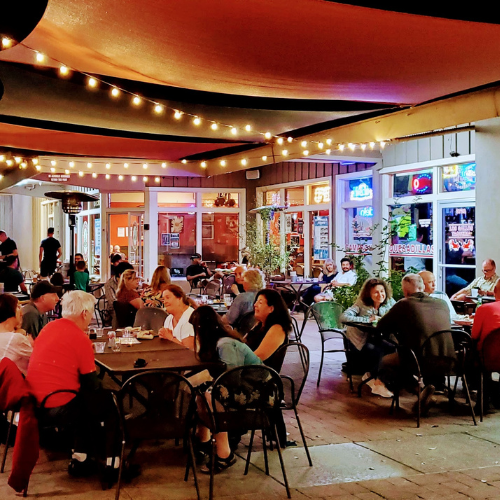 People gathered and dining on the Marsh Manor Patio at night.