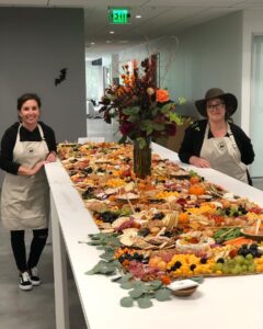 Ashley and a member of the Feast and Floral Staff beside a grazing table, a table-sized charcuterie board.