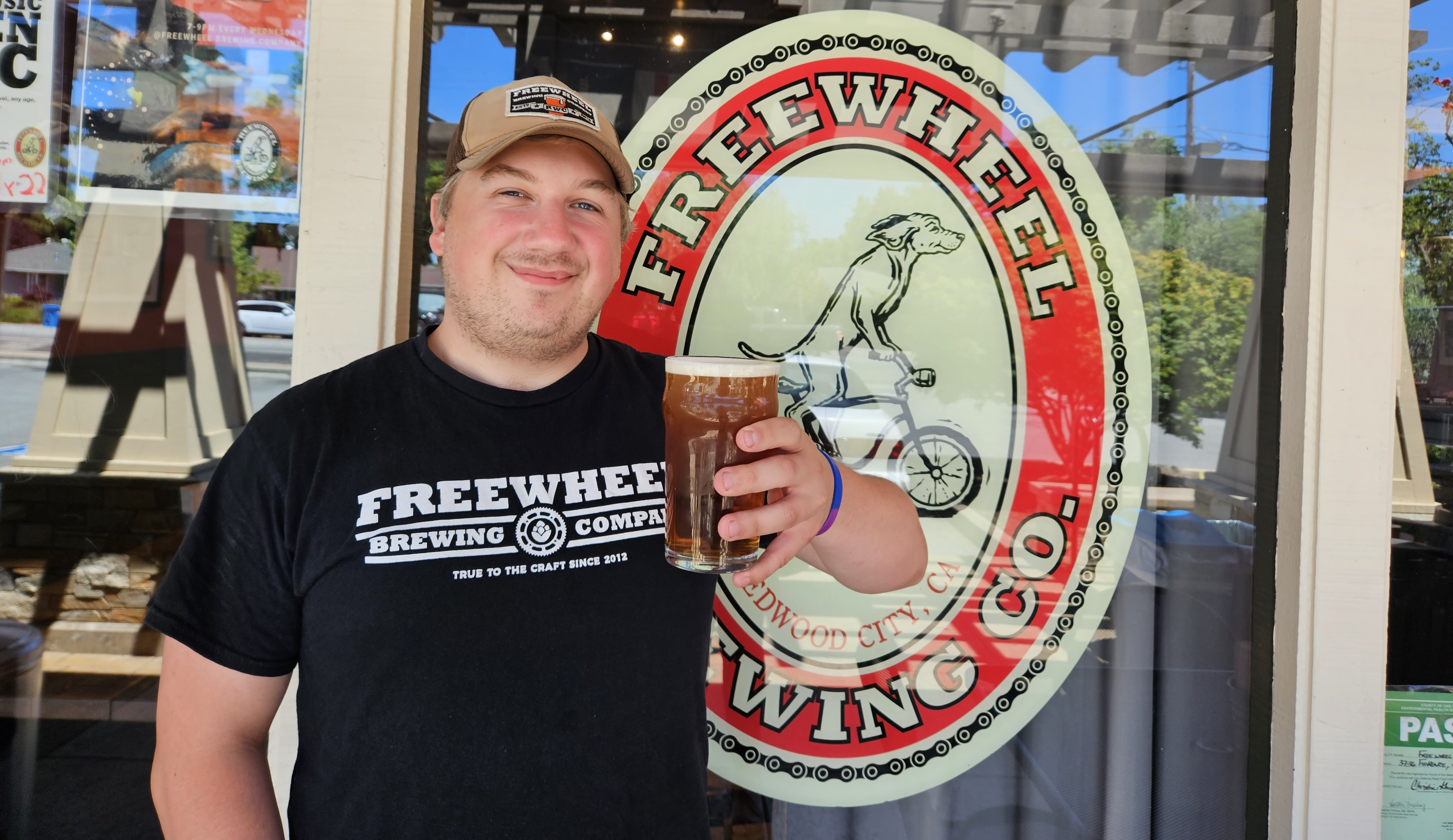 A Freewheel employee standing next to their logo on a window.