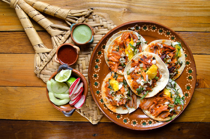 A plate of street tacos surrounded by bowls of sauces and toppings.