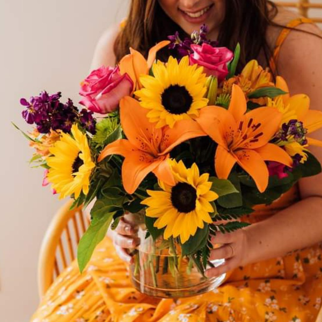 A woman holding a bouquet of flowers in warm tones.