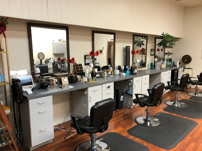 A row of salon stations at a counter, each with its own chair and mirror.