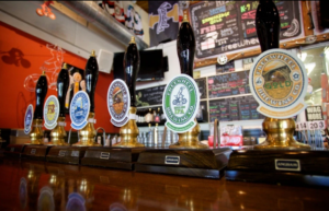 A row of beer taps with different-colored variants of the Freewheel logo.