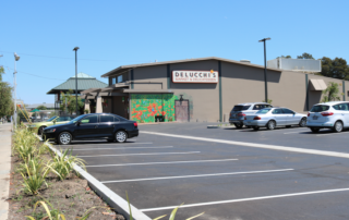 A wide shot of the West Parking Lot, with Delucchi's Market in the distance.